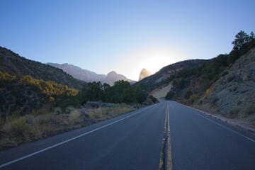 A road traveling towards desert mountains at sunrise.