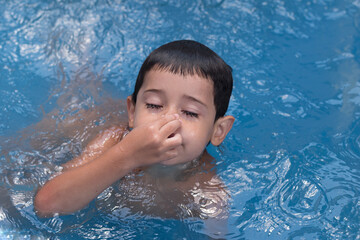 4-year-old boy covers his nose before diving underwater