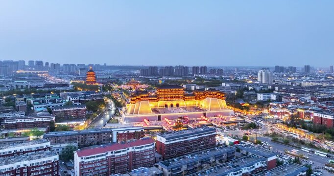 Aerial time-lapse of Yingtian Gate in Luoyang at twilight , glowing with light show brilliance amid vibrant cityscape at the ancient capital, Henan Province, China