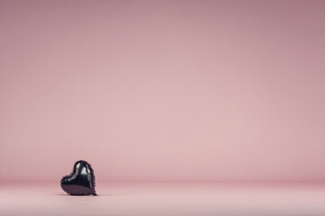 Anti valentine club concept with single black heart balloon on pink background, symbolizing loneliness and rejection, minimal style, emotional and moody atmosphere