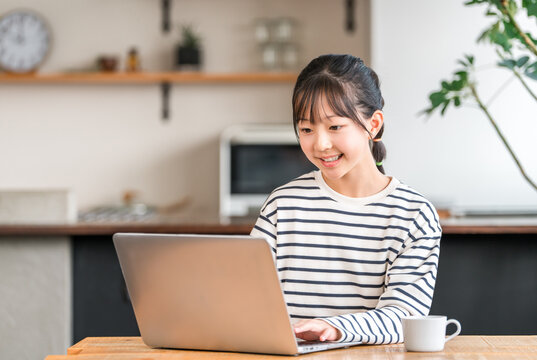 Elementary and junior high school girls using a computer in the living room/study corner at home
