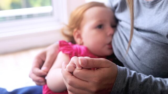 Mother breastfeeding red-haired baby girl at home, close-up view