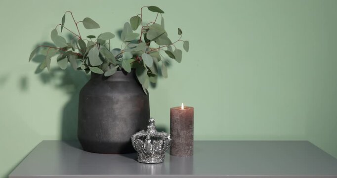 Beautiful vase with eucalyptus and other decor on grey table near olive wall
