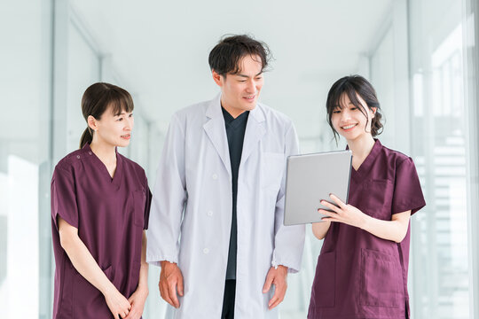 Male and female doctors, nurses, medical professionals, occupational therapists, and physical therapists talking in a hospital corridor