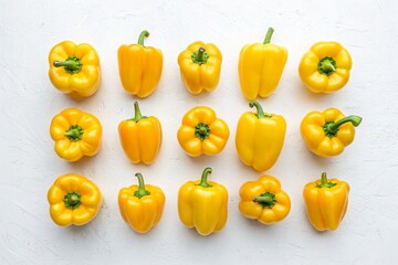 Fresh yellow bell peppers arranged in a grid pattern on a light textured background, showcasing their vibrant color and natural shape