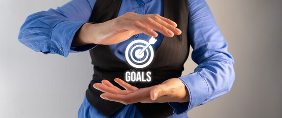 Close-up of a pair of woman's hands holding a Diana the Target icon with the word "Goals" between them