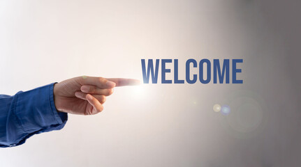 Hand of a businesswoman in a blue blouse pointing towards the word "Welcome"