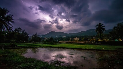 Dramatic lightning illuminates a stormy sky over a reflective rural landscape with green fields and mountains