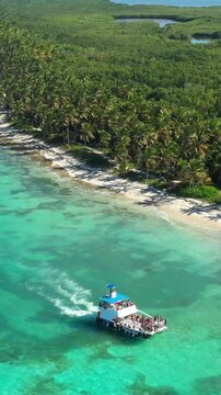 Aerial view from drone on caribbean sea with boat floating in water, tropical destination. Dominican Republic. Vertical footage