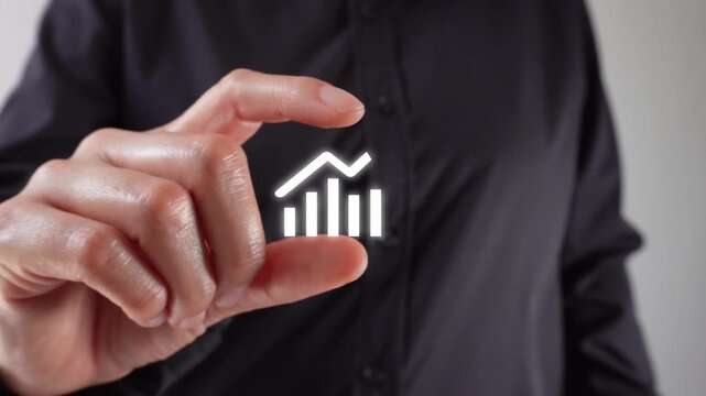 Close-up of a hand holding a growth chart with an upward-pointing arrow between two fingers