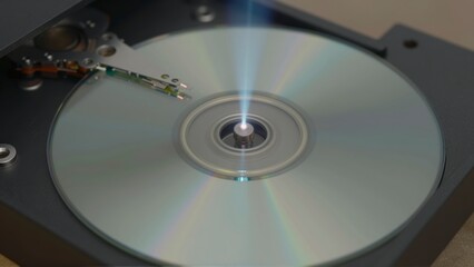 Close up of a CD or DVD disc spinning inside a player with a light beam focused on the center spindle