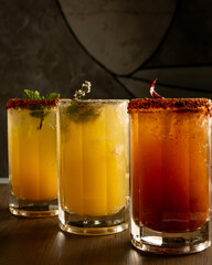 Assorted cocktails in glasses on bar counter with dramatic lighting