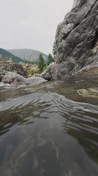 Underwater to Above Water Camera Transition in Crystal Clear Mountain River, Split Level Over-Under Shot Dipping into Pristine Stream with Landscape Reveal