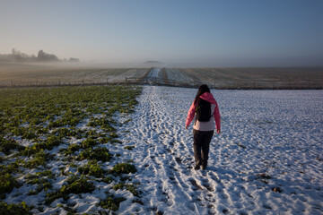 Woman hiking through snow covered fields