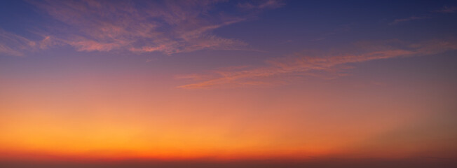 Obraz premium Beautiful panoramic sunset sky with colorful gradient clouds at twilight,A breathtaking wide-angle view of a clear sunset sky, featuring a vibrant gradient transition from deep purple and blue.