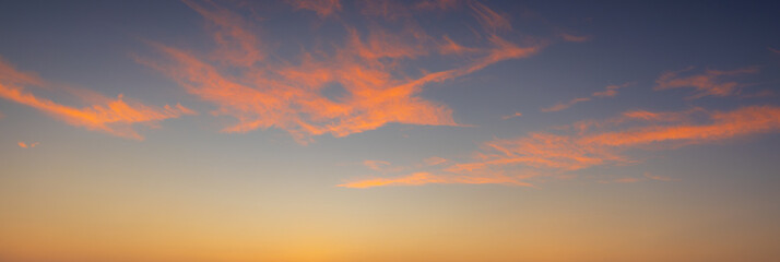 Fototapeta premium Beautiful panoramic sunset sky with colorful gradient clouds at twilight,A breathtaking wide-angle view of a clear sunset sky, featuring a vibrant gradient transition from deep purple and blue.
