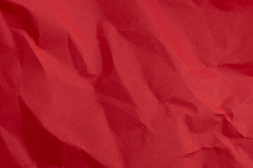 Red crinkled paper background macro,A close-up, top-down shot of a vibrant red piece of paper that has been crumpled and then flattened, creating a complex network of creases, shadows, and highlights.