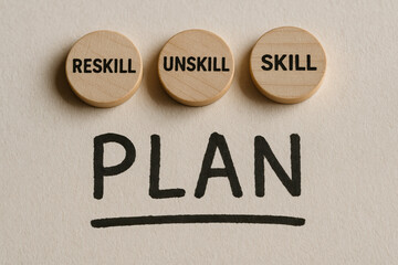 Wooden tokens with skill development terms placed on paper featuring a job learning and ability plan concept