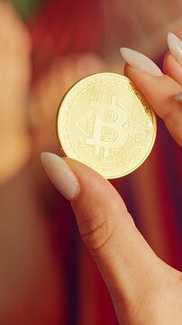 Vertical video. Close Up First Person View of Golden Bitcoin Coin Held Between Fingers With Hammock and Tropical Background Showing Financial Freedom and Digital Asset Value