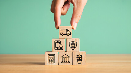 Hand placing a delivery icon block on a pyramid of business service symbols, representing strategic planning for finance, security, and growth