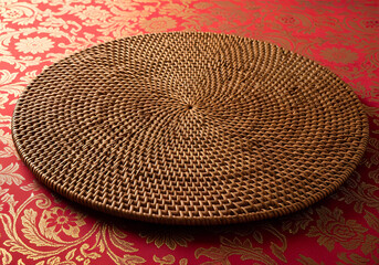Circular Woven Rattan Placemat On Red Damask Fabric