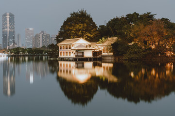 Obraz premium Serene Lake View with Traditional Pavilion and City Skyline Reflection - Huizhou West Lake
