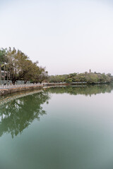 Obraz premium Tranquil Lake Reflection with Trees and Walkway - Huizhou West Lake