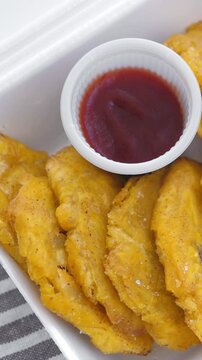 Fried platanos and sauce on plate. Sliced and cooked tostones. Rotating. Vertical footage