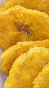 Fried platanos on plate. Sliced and cooked tostones. Rotating. Vertical footage