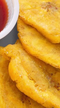 Fried platanos on plate. Sliced and cooked tostones. Rotating. Vertical footage