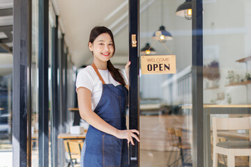 Starting a successful small business Small business owner SME Beauty Girl stands near an open sign in front of a Coffee shop. asian female barista, SME entrepreneur.
