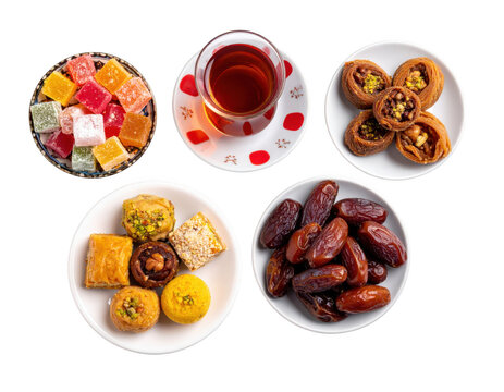 Minimalist top view of dates, mixed sweets, traditional tea glass and decorative fanous, isolated on white background