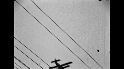 Old film, crop duster plane flying in sky. Small biplane passes behind overhead power lines strong geometric shapes. Agricultural aircraft in motion. Old film. Archival retro 1970s. Vintage archive - Powered by Adobe