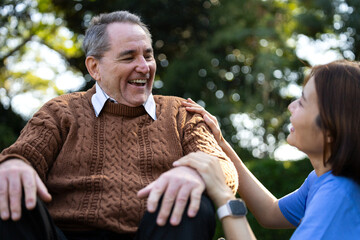Caregiver Assisting Elderly Man in Wheelchair Outdoors