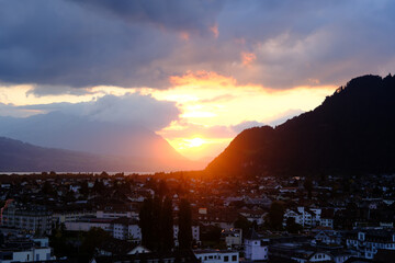 Interlaken town at sunset with mountain silhouettes and dramatic clouds