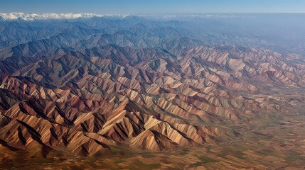 Aerial View of Rugged Mountain Range in Autumn with Snow Capped Peaks Under Clear Blue Sky Showing Brown and Green Foliage and Undulating Ridges