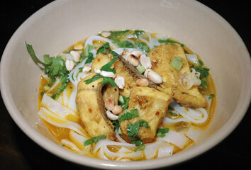 closeup of authentic mi quang noodle bowl with turmeric snakehead fish and peanuts. central vietnamese local flavor cuisine. traditional yellow rice noodle soup with herbs.