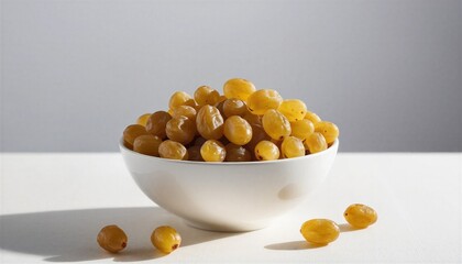Golden raisins in a white bowl on a clean white surface