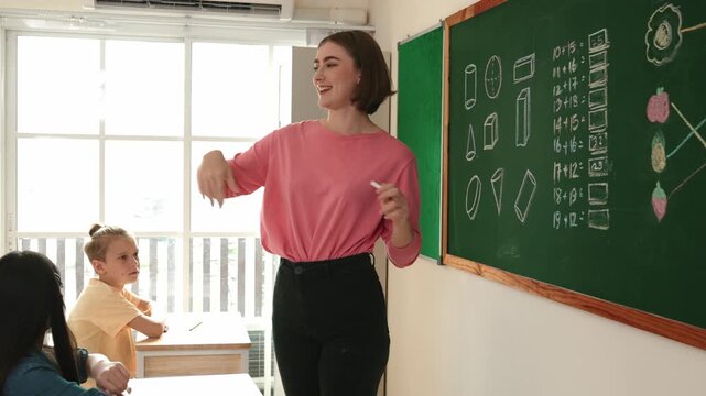 Caucasian teacher request student to raise hand up to answer question at in front of classroom. Attractive instructor calling children for writing answer in math lesson at elementary school. Pedagogy.
