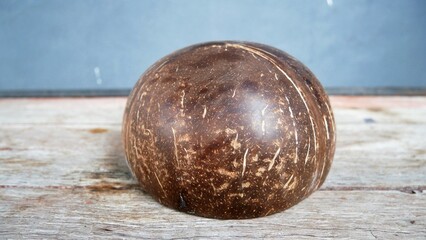 Traditional handmade bowl made from polished coconut shell on wooden table