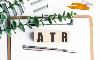 ATR abbreviation on wooden blocks with charts, clipboard, pen and plant on white background