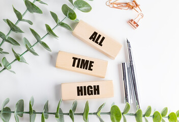All time high concept on wooden blocks with pens, leaves and stationery on white background