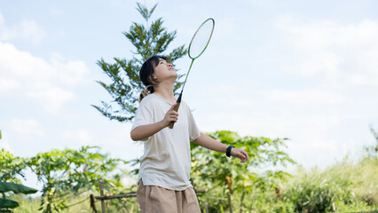 Young woman playing badminton outdoors in nature, active lifestyle and healthy recreation concept.