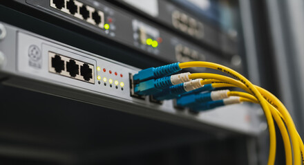Fiber optic connection on network switch ports with yellow cables, illustrating data center infrastructure and high-speed internet technology.