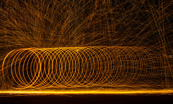 Long exposure light painting of burning steel wool creating a fiery spiral tunnel