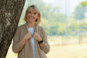 happy old woman breathe pure air from tree and have good healthy in park