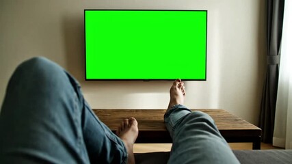 Person watching television with a green screen in a comfortable living room, leisure activity at home, and technology in daily life - Powered by Adobe