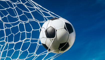 Fototapeta premium Soccer Ball Hitting Goal Net Against Blue Sky Background