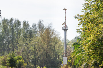Obraz premium A tower with a tsunami or emergency warning system in the coastal area in Thailand. An observation deck loudspeakers in middle of the trees to monitor. Public safety and informing the public about