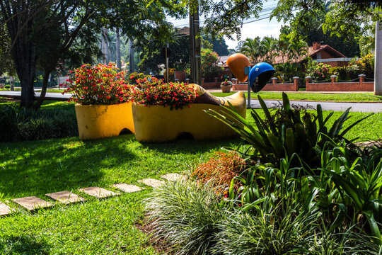 Giant yellow decorative Dutch clog planters in a public garden in Holambra II, Paranapanema, Brazil, symbolizing the city's rich Dutch immigrant heritage and cultural tradition.